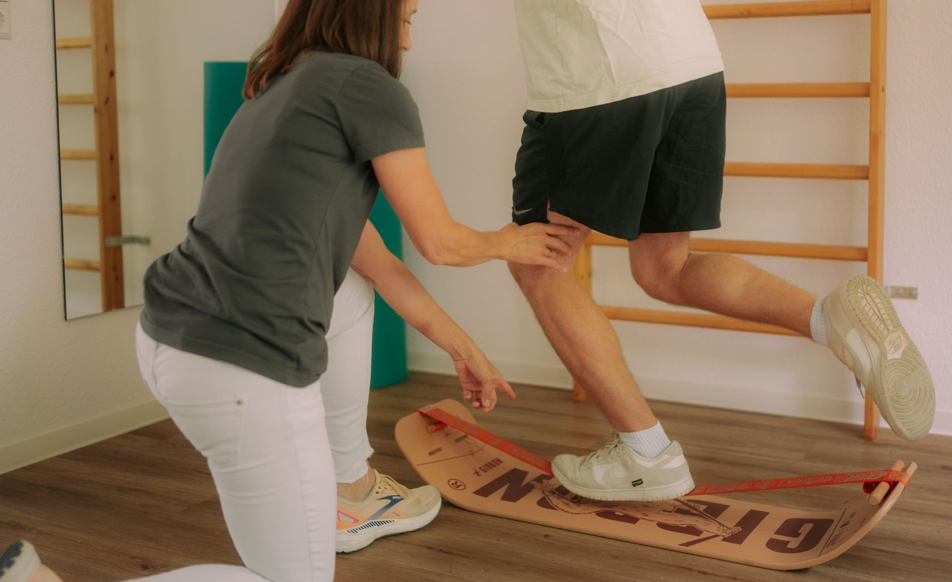 Patientin bei krankengymnastischen Übung mit Ball auf Trampolin